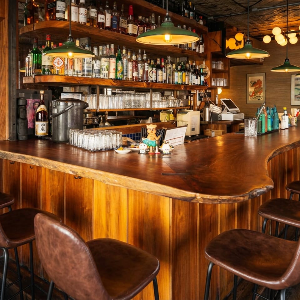 Rustic wooden bar with brown leather stools, liquor bottles, and warm pendant lights.