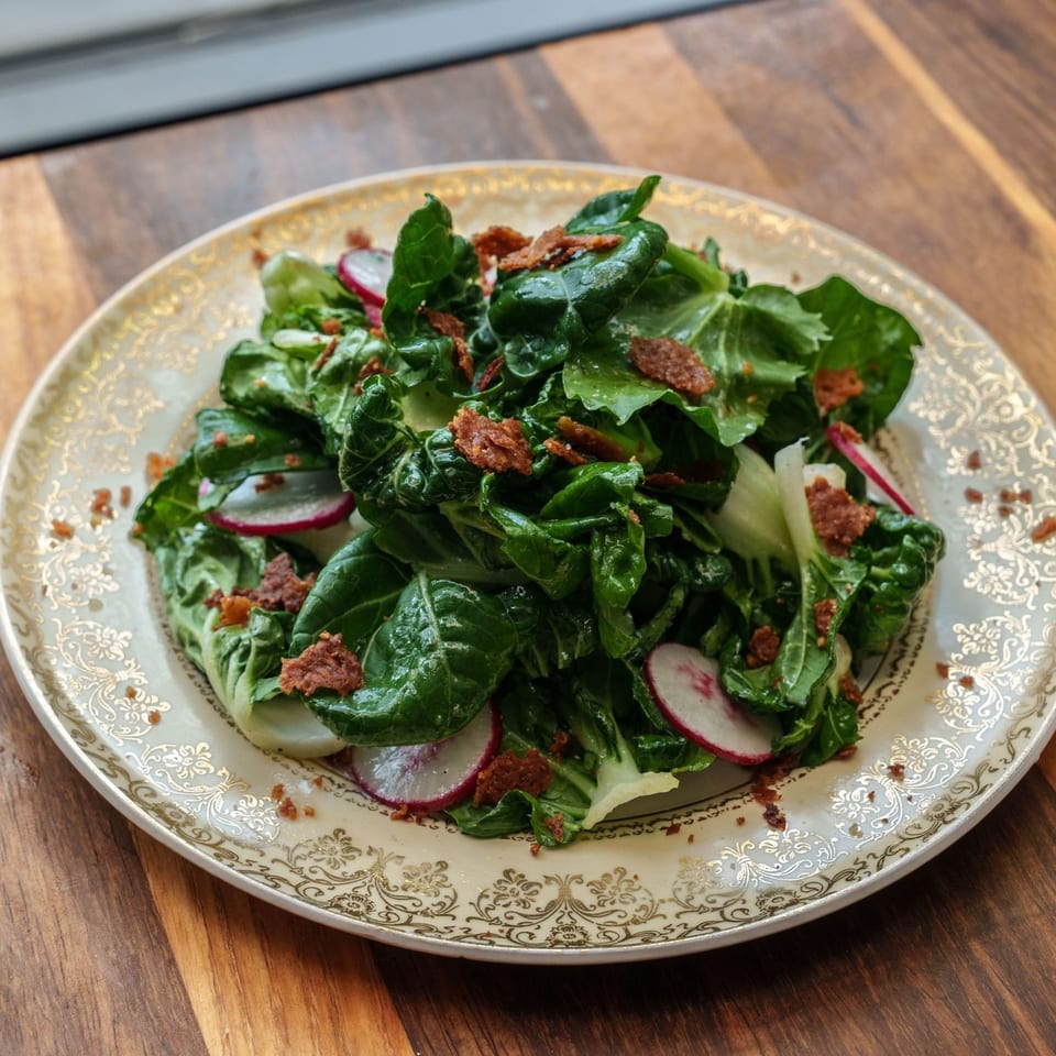 Vibrant green salad with sliced radishes and crispy bacon bits on an ornate plate.